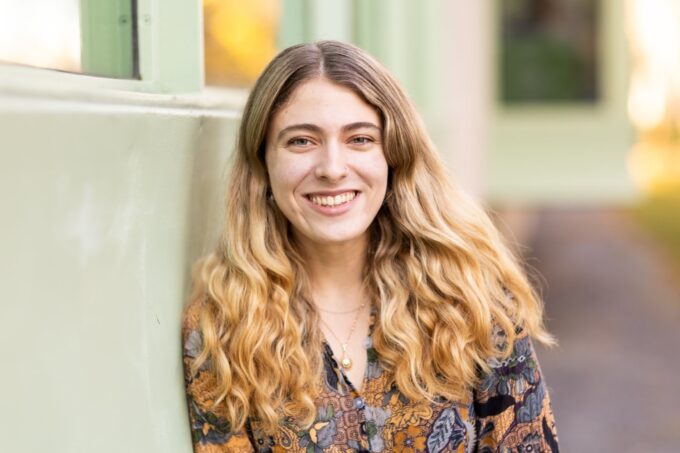 Aviva Intveld, leaning against a wall and smiling.