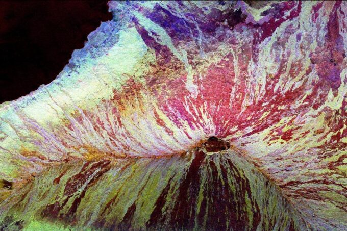 An aerial view of Mauna Loa showing the volcano in pinks, yellows and purples.