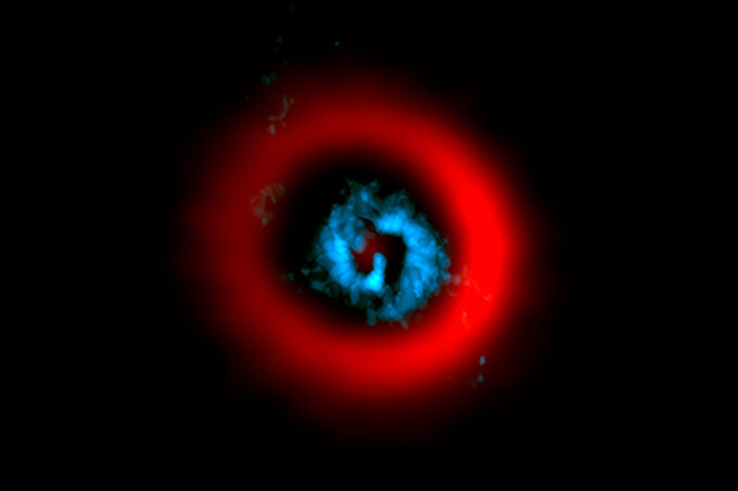 a picture of the star AB Aurigae; it has a spiraling blue center with a red ring surrounding it.